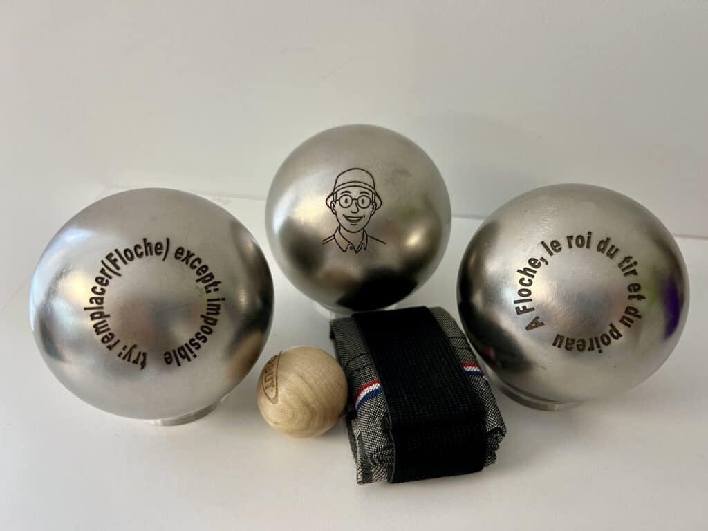 Boules de pétanque personnalisées avec portrait et message humoristique gravés sur métal.