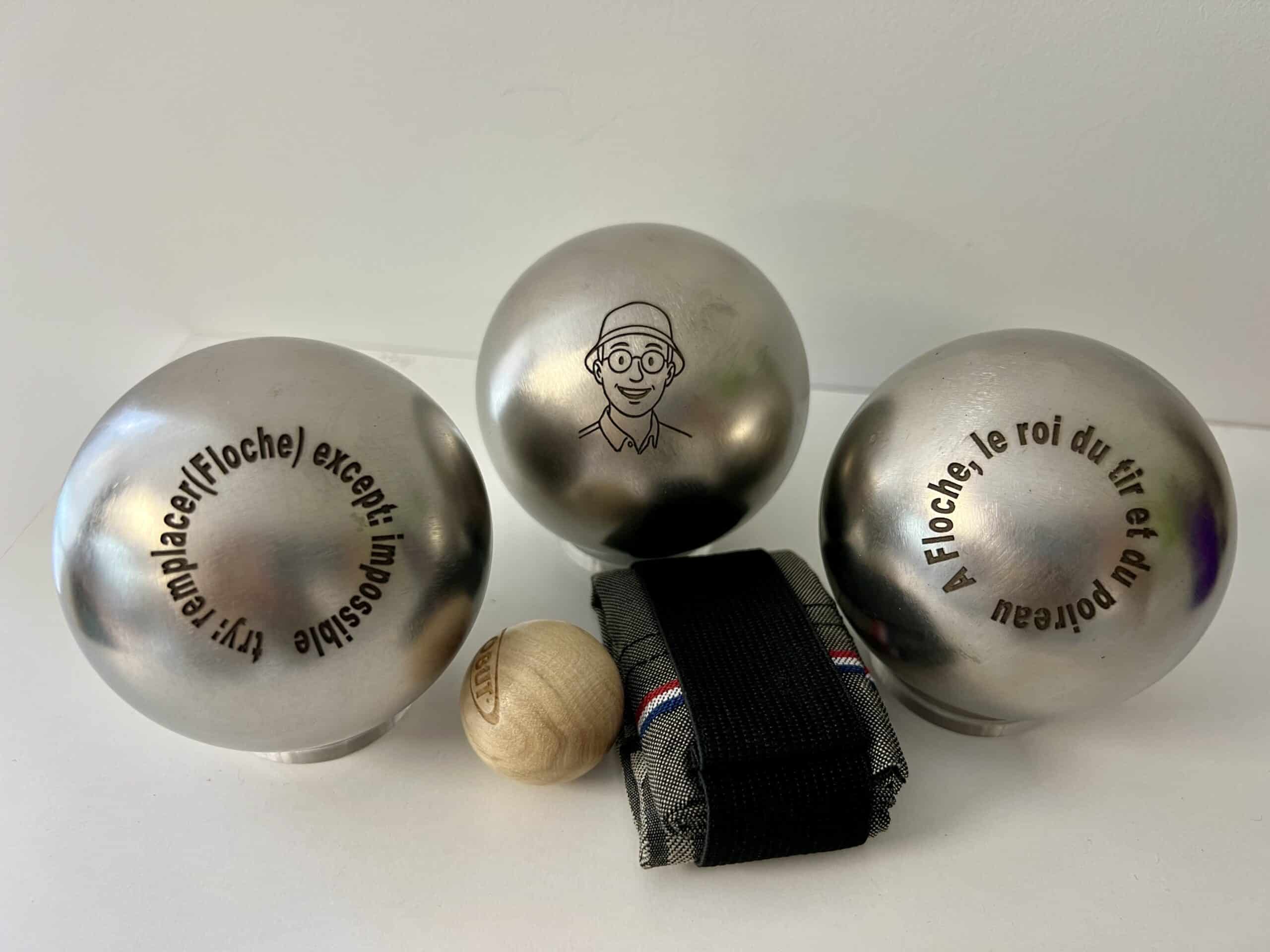 Boules de pétanque personnalisées avec portrait et message humoristique gravés sur métal.
