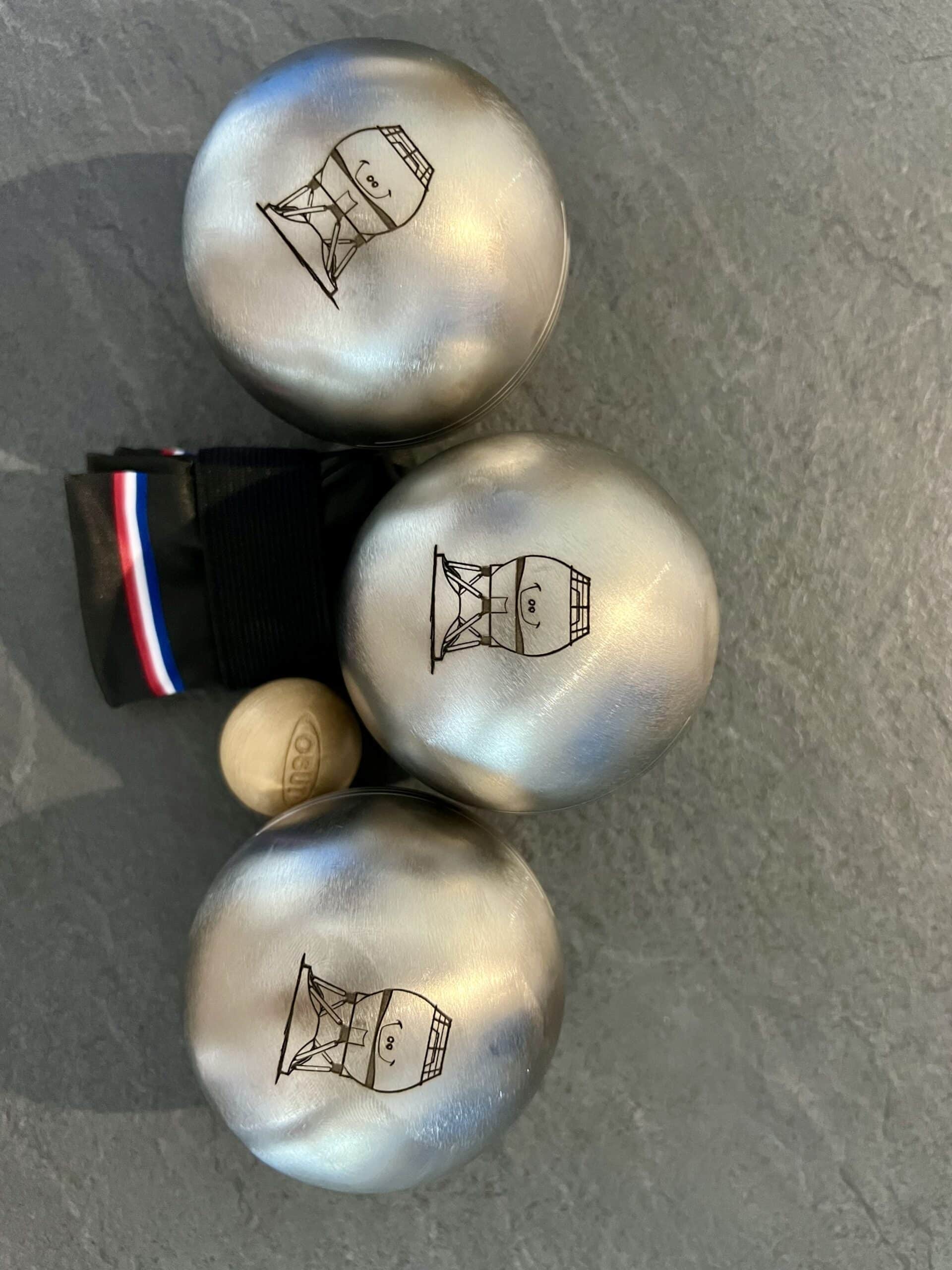Boules de pétanque personnalisées avec portraits dessinés gravés sur métal.