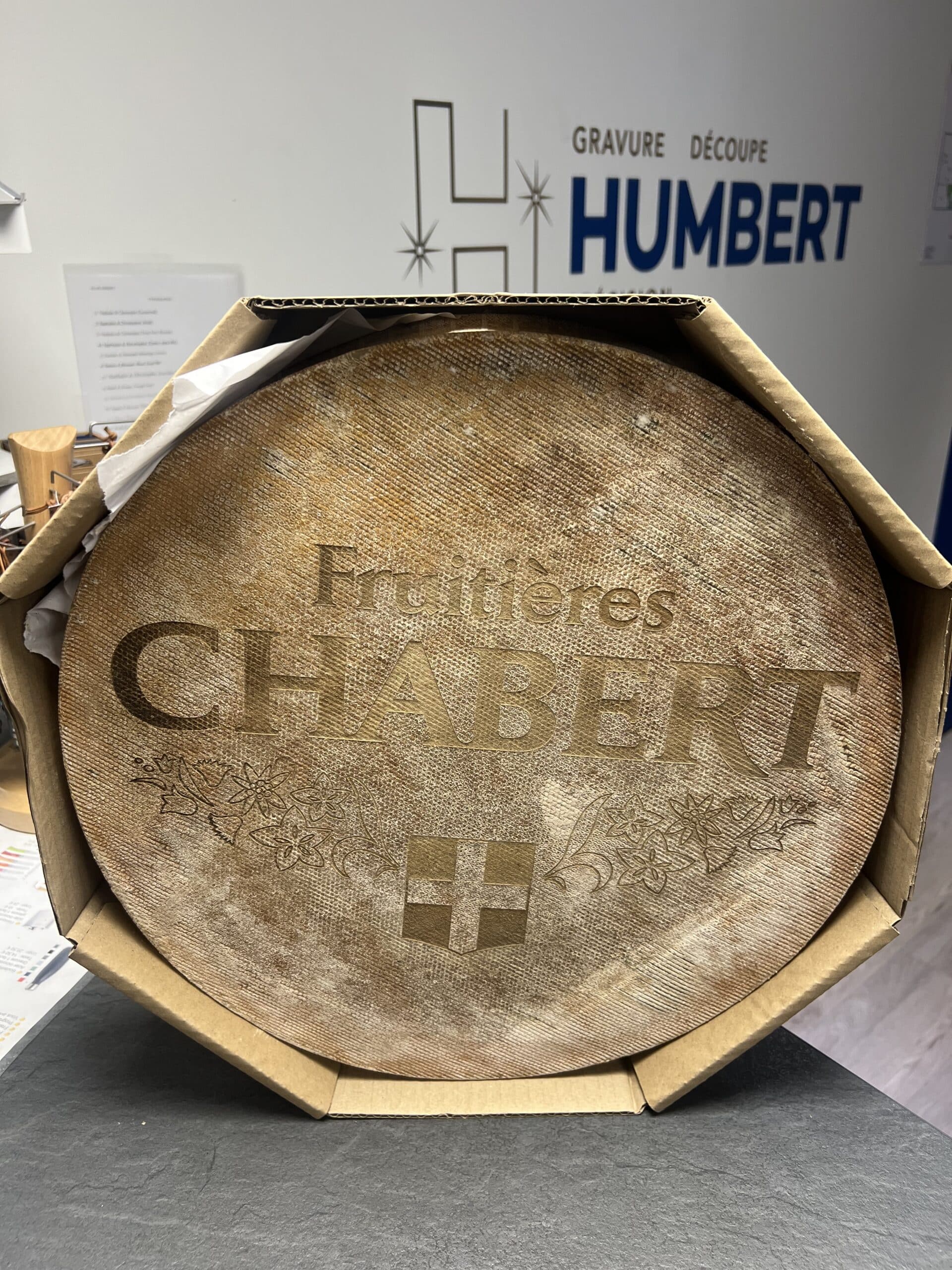 Meule de fromage AOP Abondance personnalisée par gravure laser avec le logo Fruitières Chabert dans son emballage.